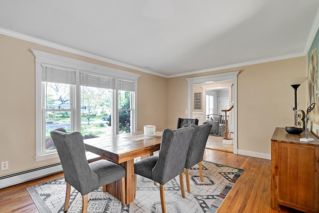 dining room with light wood finished floors, baseboards, baseboard heating, and ornamental molding