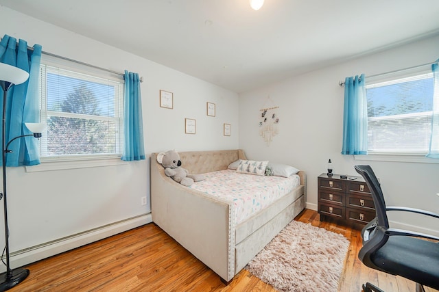 bedroom with wood finished floors and baseboard heating