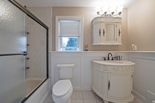 full bathroom with tile patterned flooring, toilet, a decorative wall, and vanity