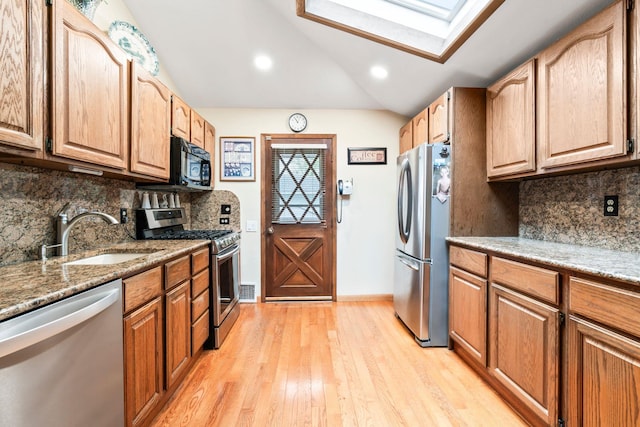 15 Kevin Rd, Commack, NY 11725 - kitchen featuring appliances with stainless steel finishes, a sink, a skylight, decorative backsplash, and vaulted ceiling