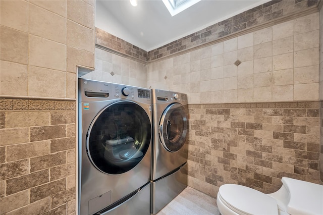 washroom with tile walls, independent washer and dryer, and a skylight