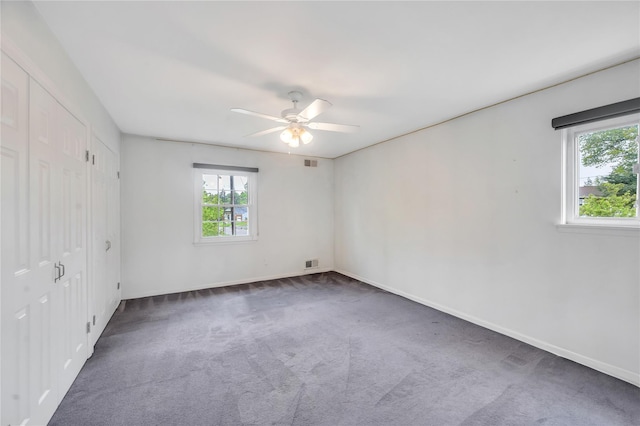 carpeted empty room featuring healthy amount of natural light, ceiling fan, and baseboards
