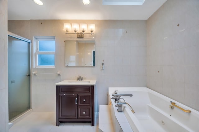 bathroom with a shower stall, tile walls, a jetted tub, vanity, and tile patterned floors