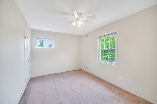 empty room with plenty of natural light, light colored carpet, and ceiling fan