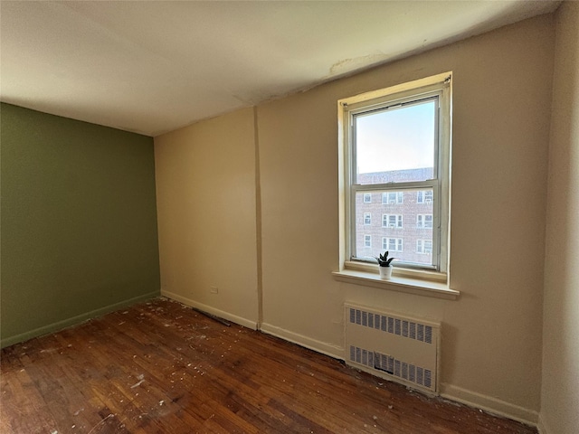 spare room with wood-type flooring, baseboards, and radiator heating unit