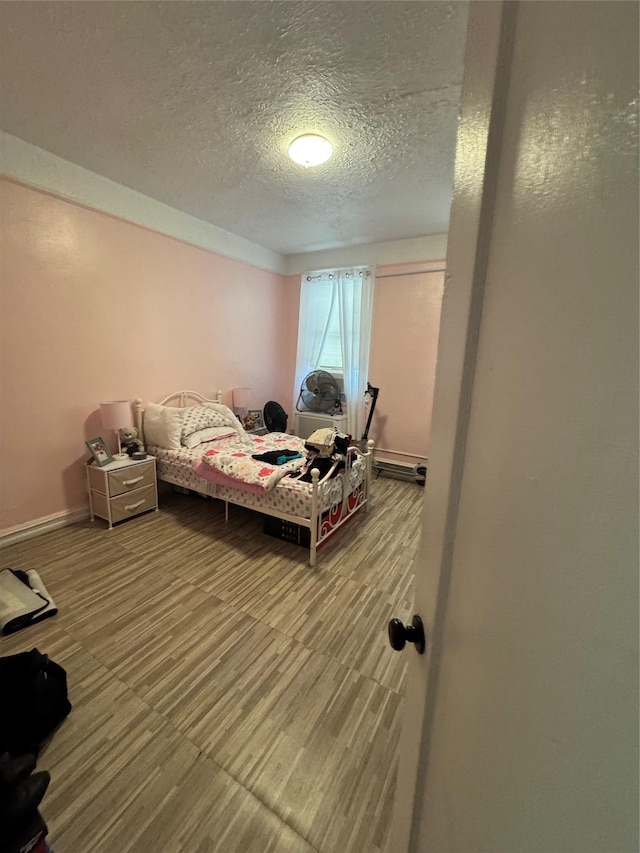 1171 Leland Ave, Bronx, NY 10472 - bedroom with a textured ceiling, baseboards, and a baseboard heating unit
