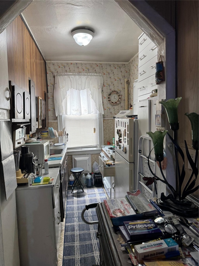 1171 Leland Ave, Bronx, NY 10472 - kitchen featuring brown cabinets, wallpapered walls, freestanding refrigerator, light countertops, and white microwave