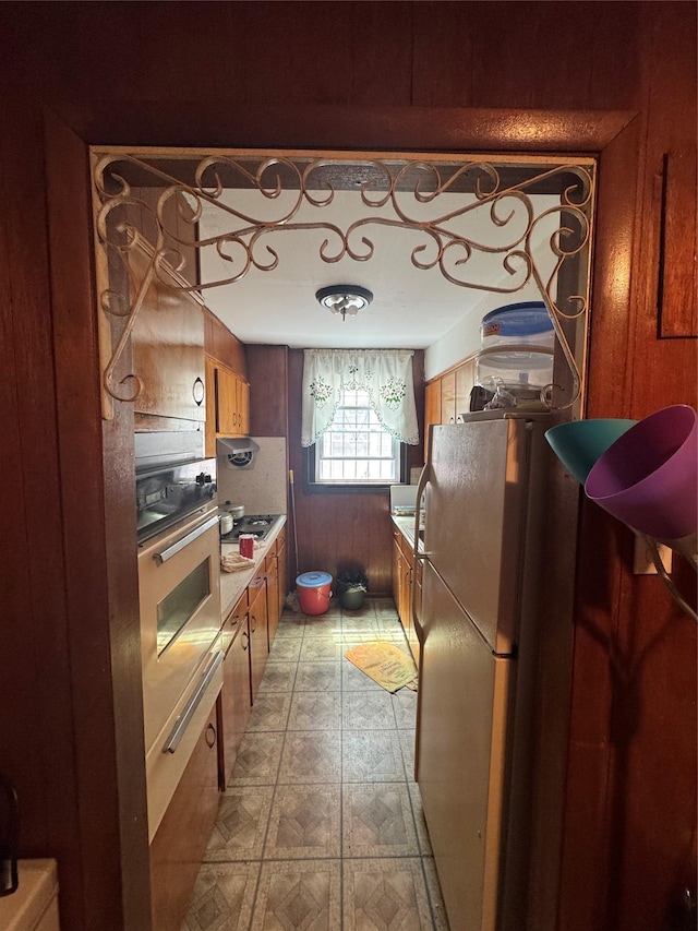 1171 Leland Ave, Bronx, NY 10472 - kitchen with freestanding refrigerator, brown cabinetry, stainless steel oven, gas stovetop, and light floors