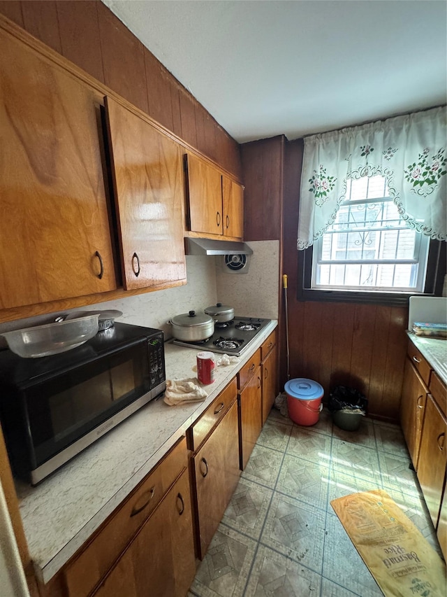 1171 Leland Ave, Bronx, NY 10472 - kitchen featuring black microwave, stainless steel gas cooktop, brown cabinetry, light countertops, and light flooring