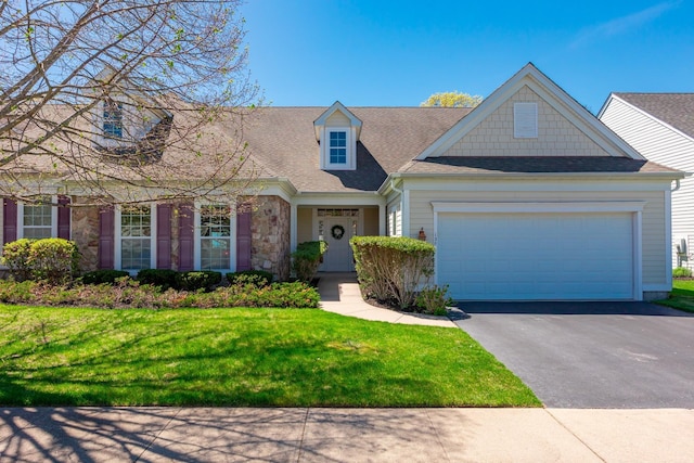 view of front facade with driveway, roof with shingles, a garage, a front lawn, and stone siding