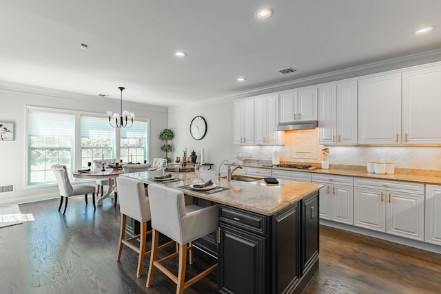 kitchen featuring dark wood-style flooring, a sink, ornamental molding, under cabinet range hood, and white cabinetry