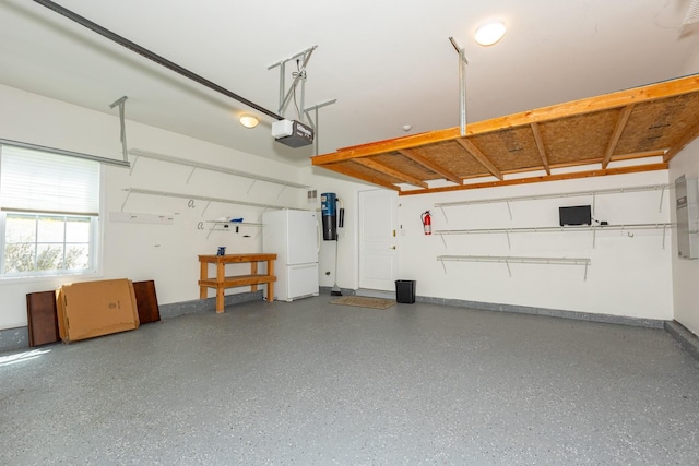 garage featuring baseboards, a garage door opener, and freestanding refrigerator
