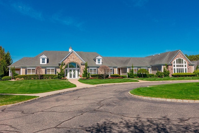 view of front of property featuring french doors, a chimney, a front lawn, and stone siding