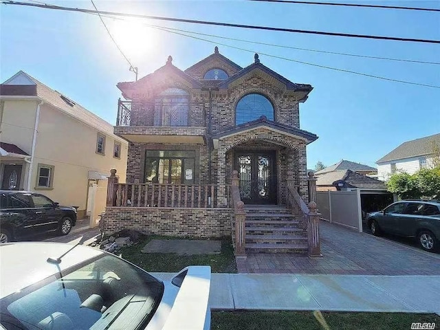 french country inspired facade featuring brick siding, french doors, and a balcony