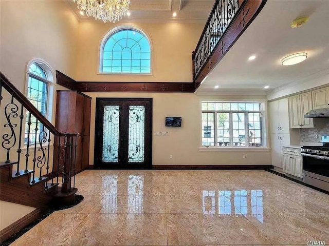 entrance foyer with stairs, ornamental molding, french doors, and plenty of natural light