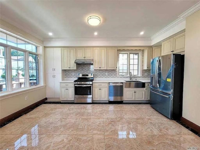 kitchen featuring under cabinet range hood, baseboards, appliances with stainless steel finishes, and crown molding