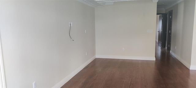 spare room with baseboards and wood finished floors