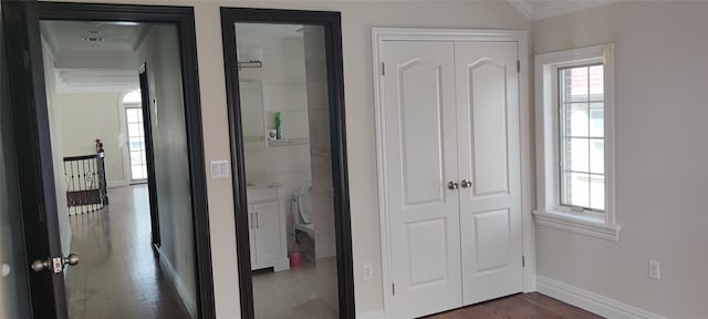 hallway featuring dark wood-style flooring, baseboards, ornamental molding, and a wealth of natural light