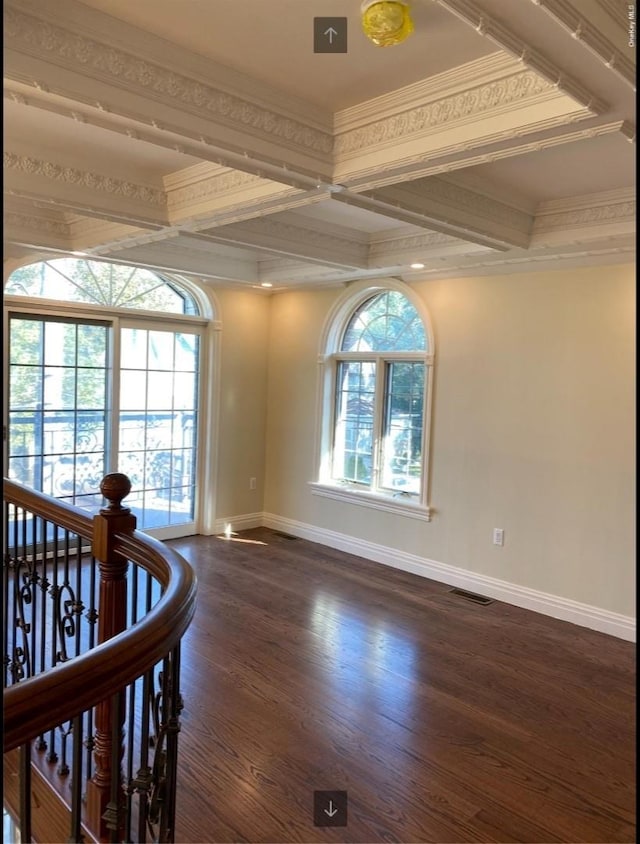 empty room featuring beam ceiling, baseboards, dark wood-type flooring, visible vents, and coffered ceiling