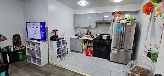 50-05 46th St, Woodside, NY 11377 - kitchen featuring freestanding refrigerator, gas stove, gray cabinetry, backsplash, and under cabinet range hood