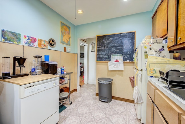 kitchen featuring brown cabinets, light countertops, recessed lighting, baseboards, and refrigerator