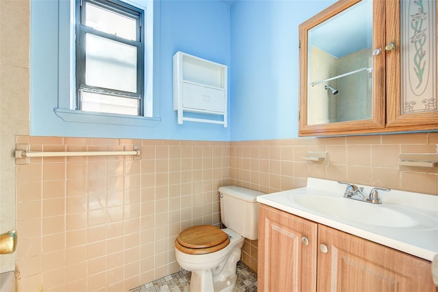 full bath with tile walls, wainscoting, walk in shower, vanity, and toilet