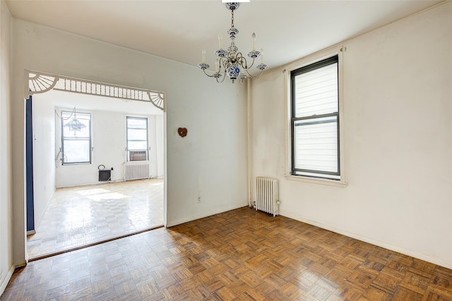 unfurnished room featuring baseboards, a notable chandelier, and radiator heating unit