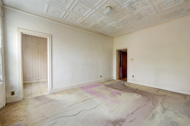 carpeted spare room with crown molding, baseboards, and an ornate ceiling