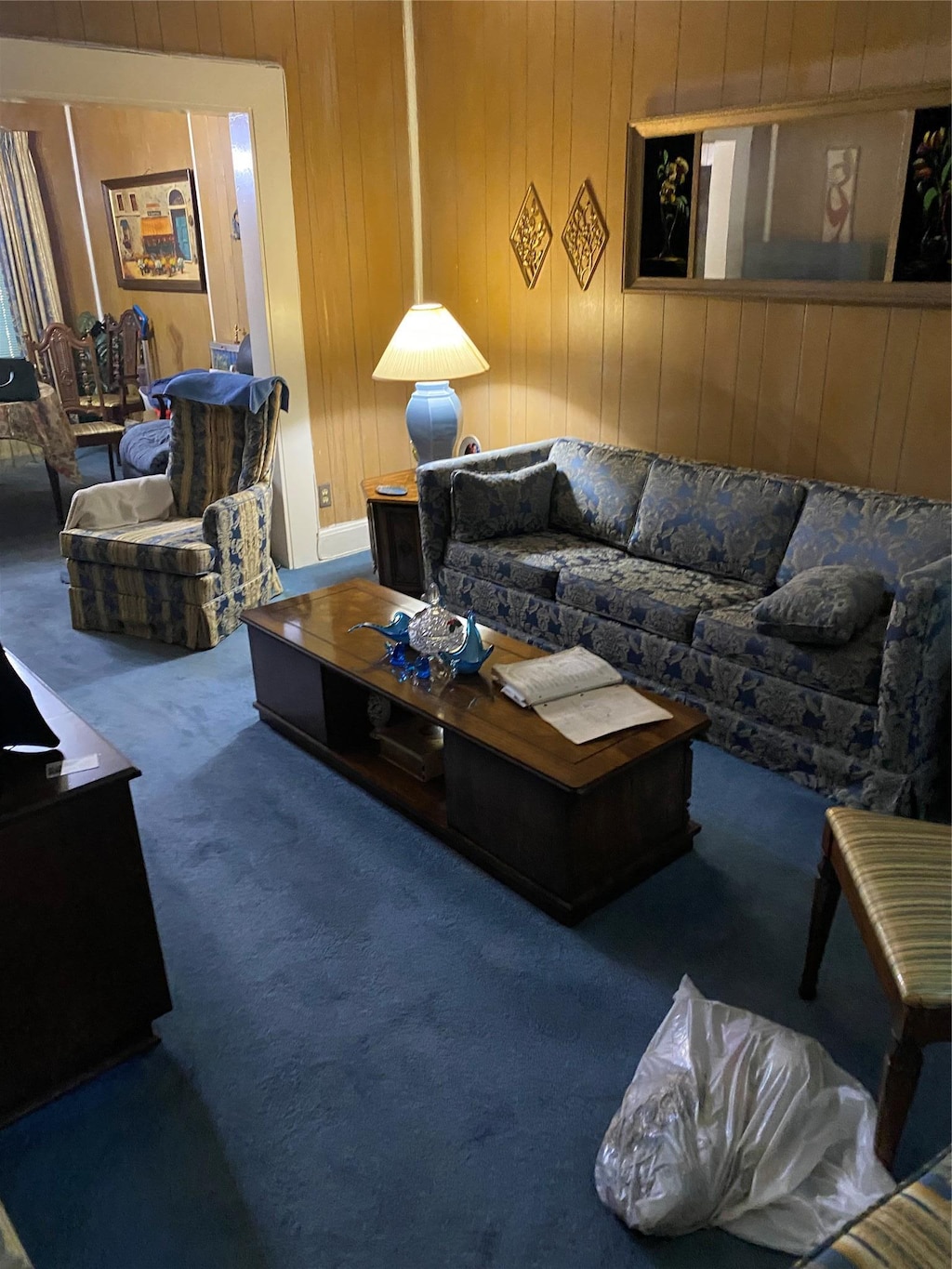 living area with carpet and wood walls