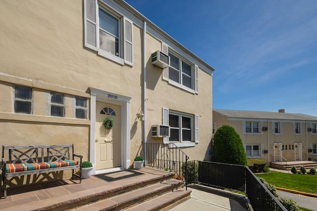 exterior space featuring an AC wall unit, stucco siding, and a wall unit AC