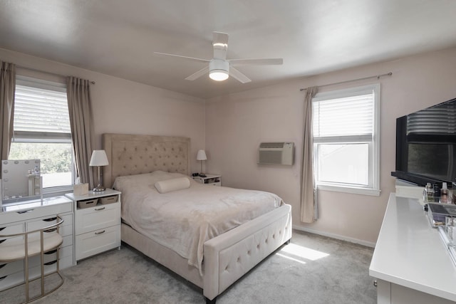 bedroom featuring baseboards, ceiling fan, a wall unit AC, and light colored carpet