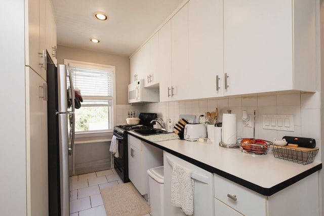 kitchen with freestanding refrigerator, black range with gas stovetop, recessed lighting, white cabinetry, and tasteful backsplash