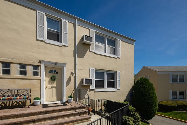 multi unit property with fence, stucco siding, and a wall mounted AC
