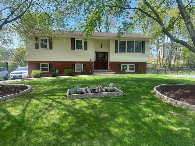 bi-level home with a front lawn and fence