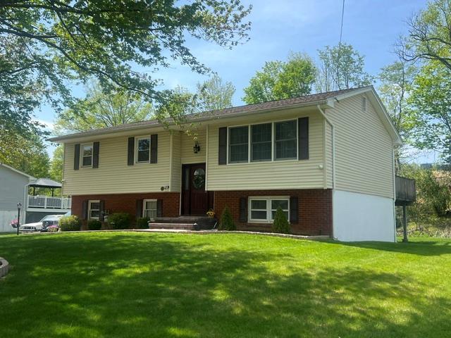 raised ranch with brick siding and a front yard