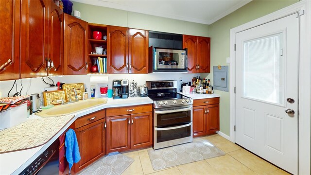 kitchen featuring crown molding, light countertops, a sink, stainless steel appliances, and light tile patterned flooring