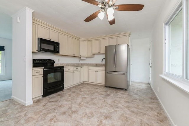 900 Cedar Dr, Southold, NY 11971 - kitchen featuring black appliances, cream cabinetry, plenty of natural light, and light countertops