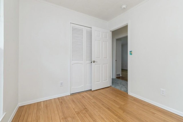 900 Cedar Dr, Southold, NY 11971 - unfurnished bedroom with light wood finished floors, ornamental molding, baseboards, and a closet
