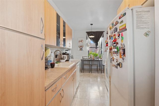 kitchen with light brown cabinetry, a sink, light countertops, glass insert cabinets, and white appliances