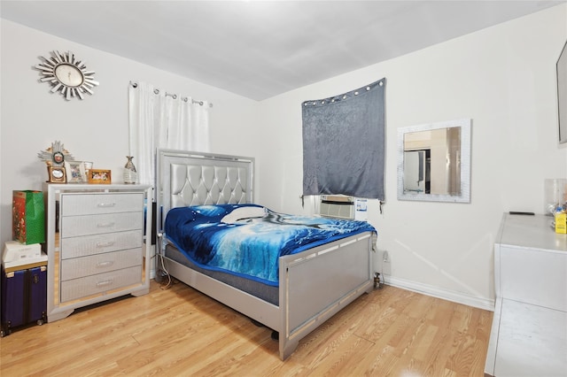 bedroom featuring baseboards, light wood finished floors, and cooling unit