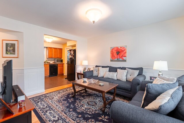 living area featuring a wainscoted wall, light wood-type flooring, and a decorative wall