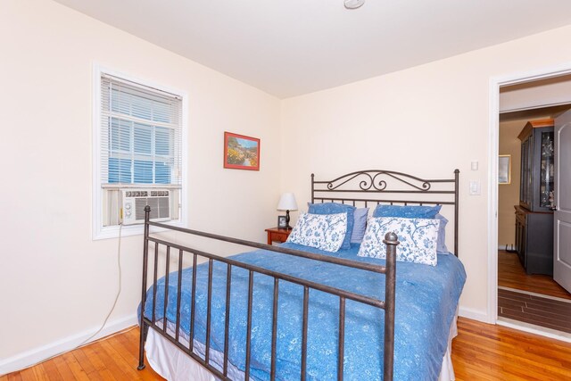 bedroom with wood finished floors, baseboards, and cooling unit