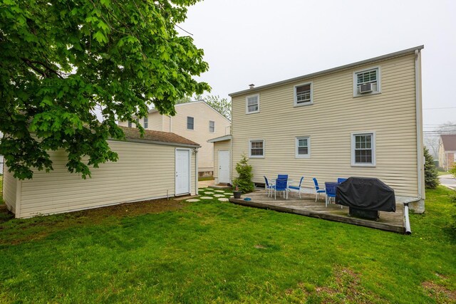 back of property with an outdoor structure, a deck, a yard, and cooling unit