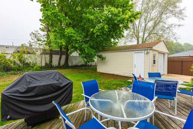 wooden terrace featuring outdoor dining area, an outbuilding, and grilling area