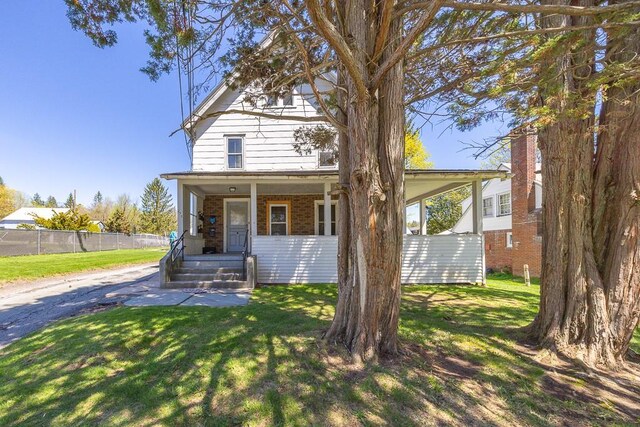 view of front facade with fence, a front lawn, and brick siding