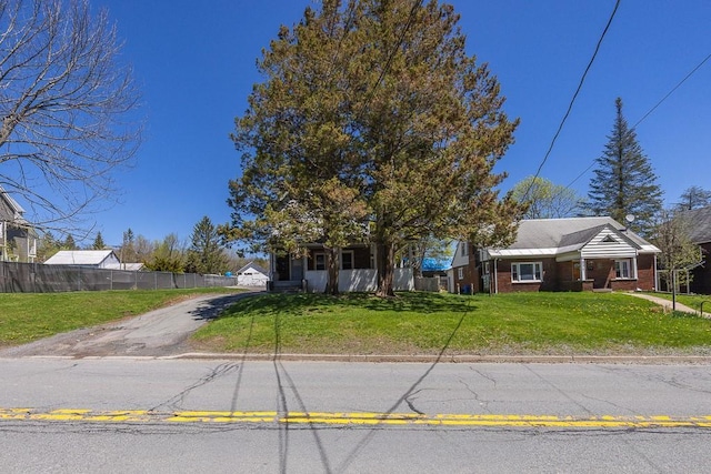 view of front of house featuring brick siding, fence, driveway, and a front yard