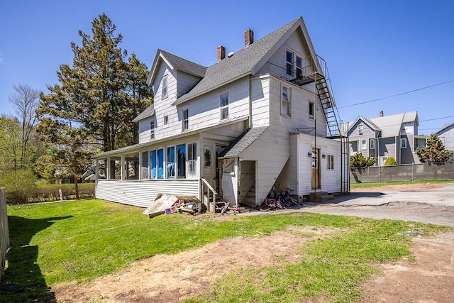 view of front of property featuring fence, roof with shingles, a front yard, entry steps, and a chimney