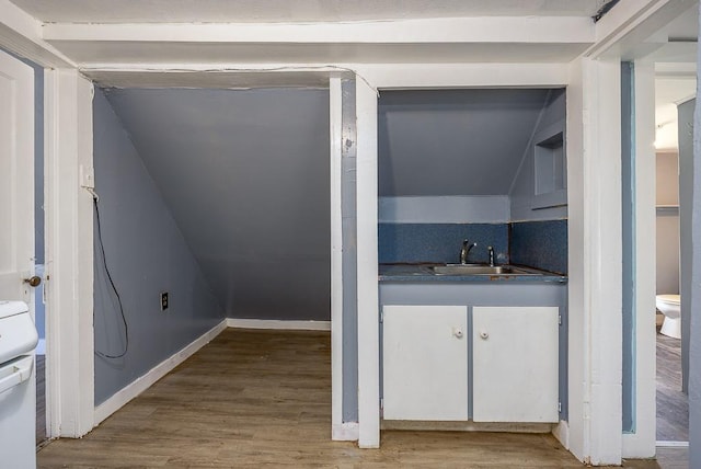 interior space featuring baseboards, a sink, and wood finished floors