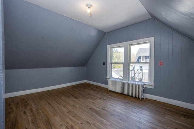 additional living space featuring radiator heating unit, baseboards, vaulted ceiling, and wood finished floors