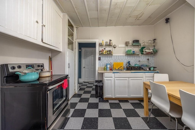 kitchen featuring electric range, open shelves, light countertops, dark floors, and white cabinetry